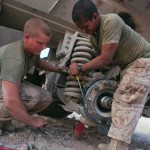 Two marines changing the tire on a military vehicle.
