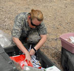 A women searches through medical supplies in the desert.