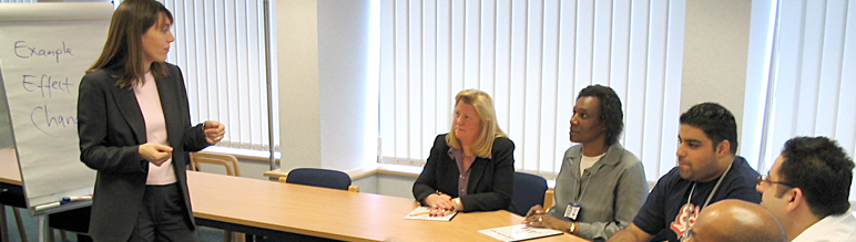 A women in a conference room speaking to people.